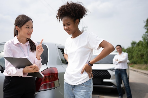 women drivers talk insurance agent examining damaged car customer checks report claim form after accident concept insurance advice auto repair shop car traffic accidents